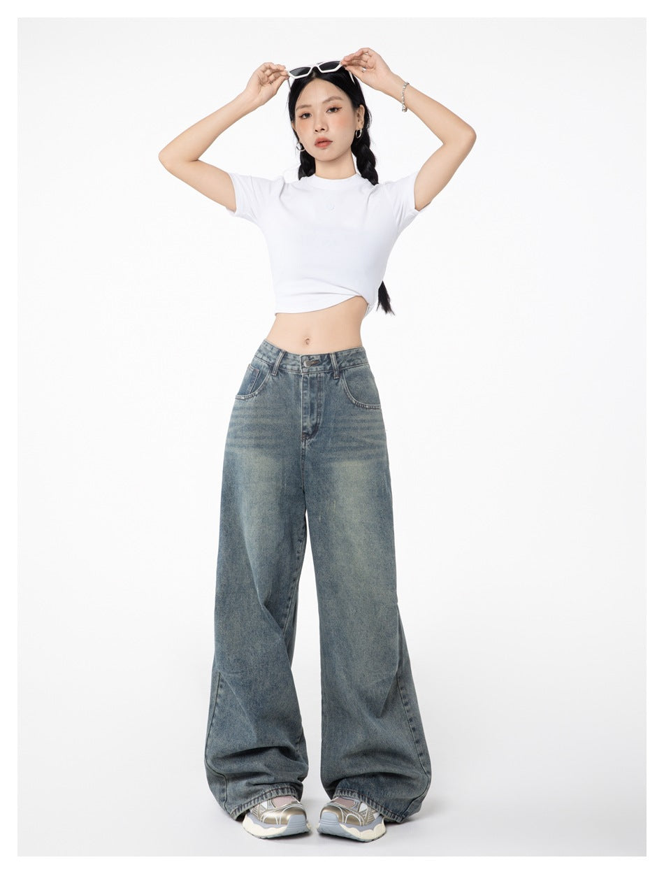 Model wearing light blue wide-leg jeans with a white cropped tee, arms raised, full-length front view