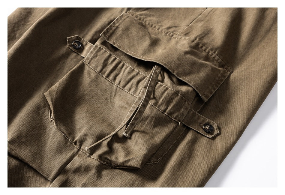 Close-up of a khaki-brown cargo pocket with buttoned tabs, a flap, and a drawcord.