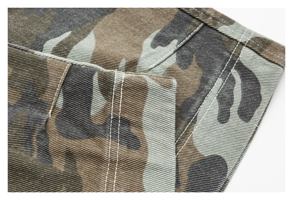 Close-up of a stitched panel seam on brown, black and sage camouflage trouser fabric.
