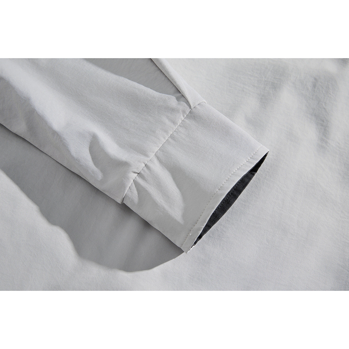 Close-up of a light gray jacket sleeve cuff with a dark inner edge and visible stitching.