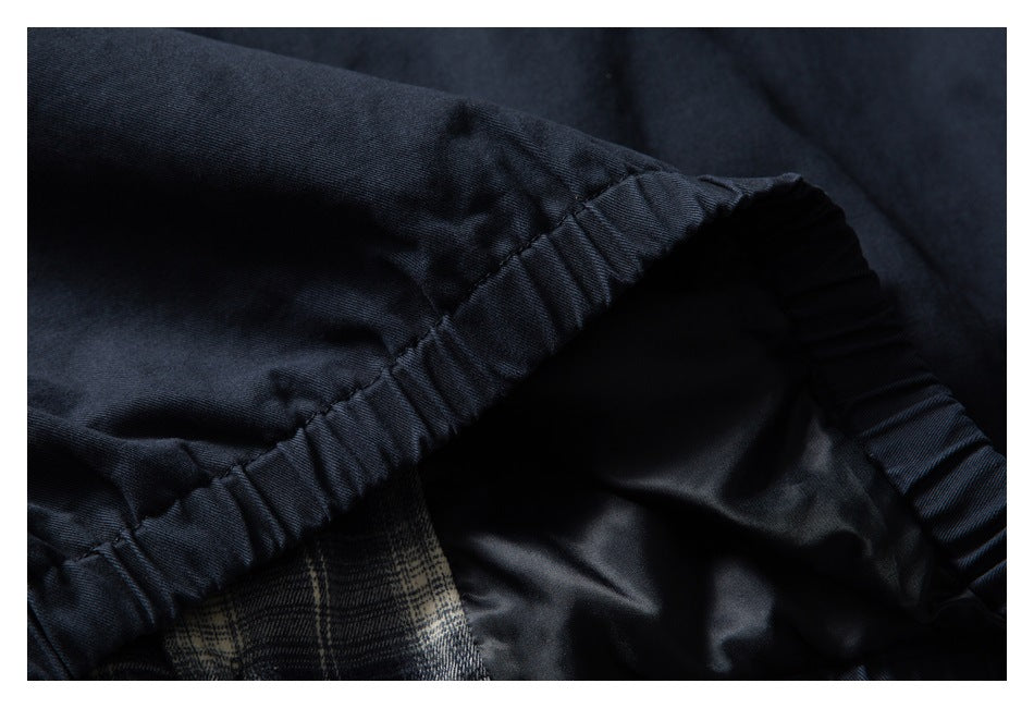 Close-up of a gathered elastic seam with dark navy fabric, plaid lining, and a smooth black interior.