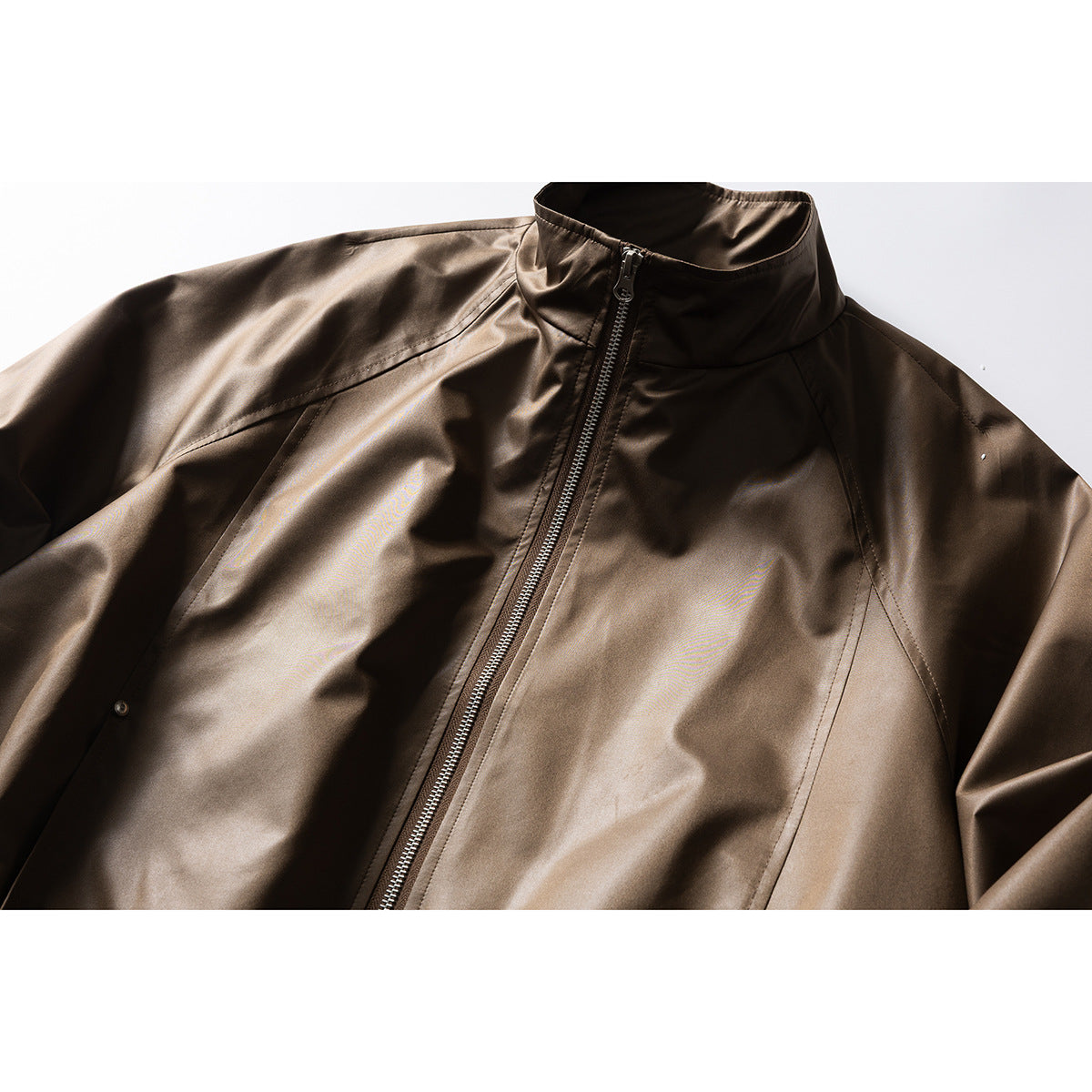 Close-up of a glossy dark brown jacket front with a stand collar, central zipper, and panel seams.