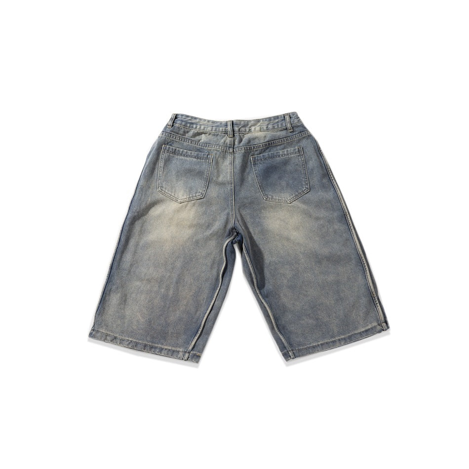 Back view of washed gray-blue denim Bermuda shorts with two rear patch pockets and wide straight legs.