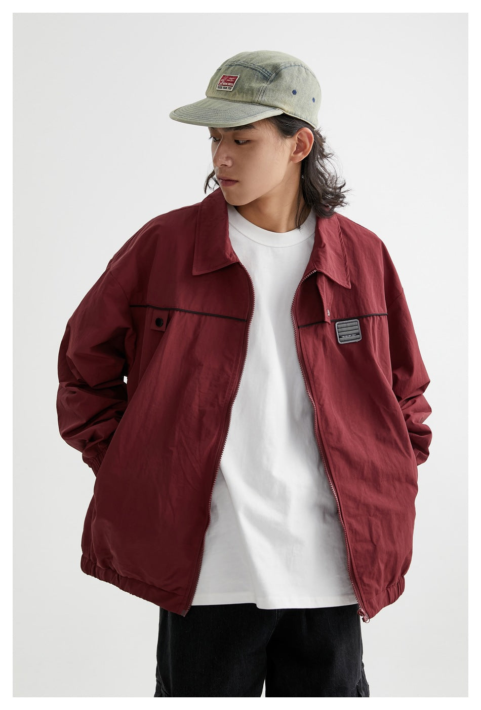 Front view of a model wearing an open burgundy jacket with black chest trim over a white shirt.