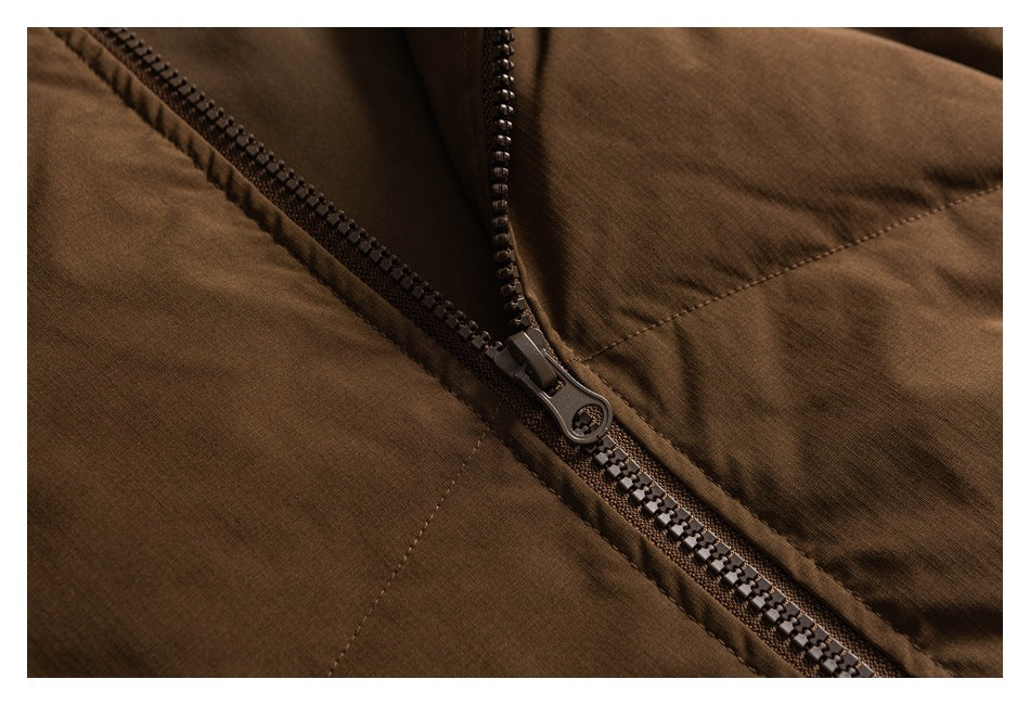 Close-up of a dark zipper and stitched seam on a brown jacket.