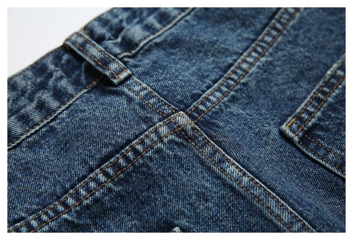 Close-up of blue denim seams, belt loop and pocket edge with contrasting stitching.
