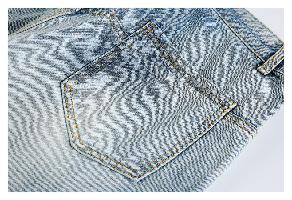 Close-up of a back patch pocket with golden contrast stitching on light-wash jeans.
