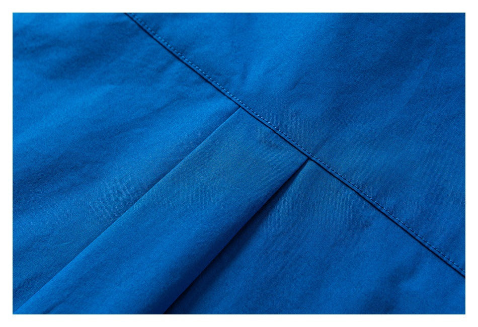 Close-up of bright blue fabric showing a folded pleat beneath a diagonal stitched seam.