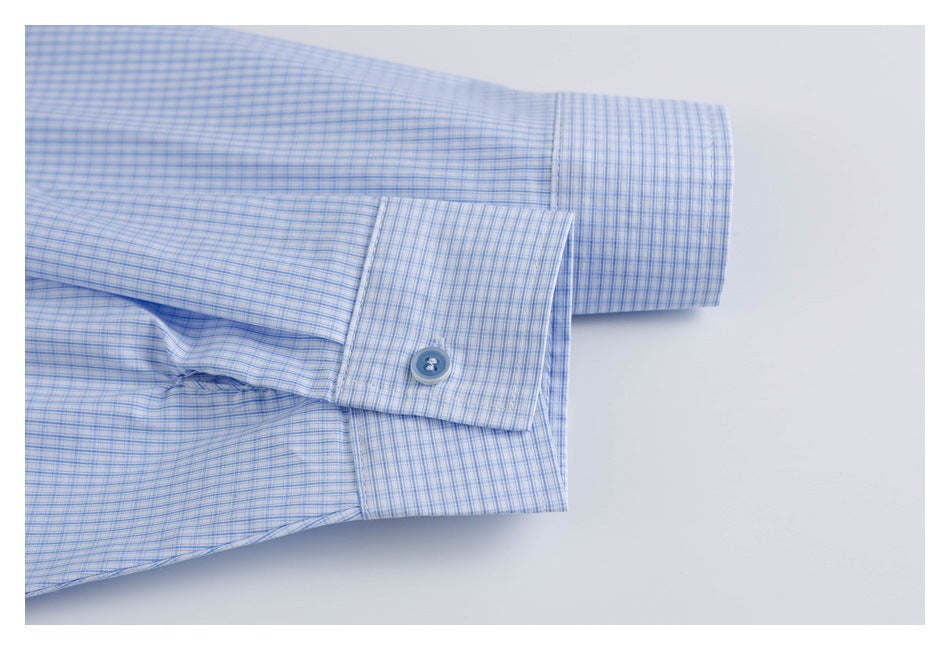 Close-up of a buttoned cuff on a light blue fine-check shirt.