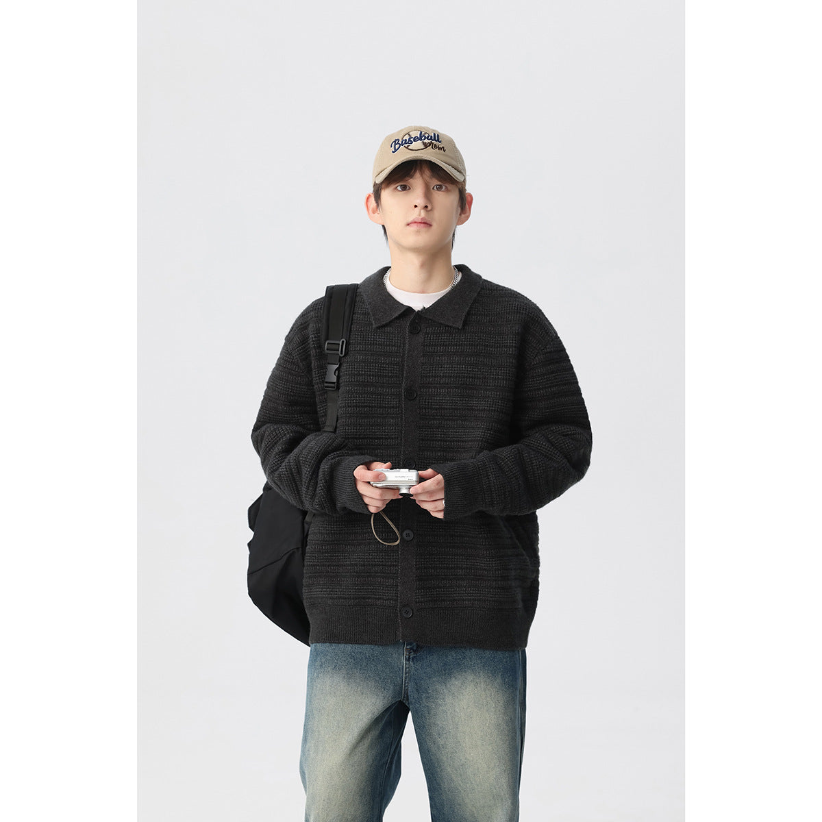 Model wearing a charcoal textured knit cardigan with a collar and dark buttons, carrying a black shoulder bag.