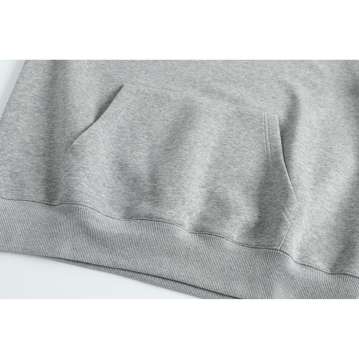 Close-up of the gray pullover's large front kangaroo pocket and ribbed hem.