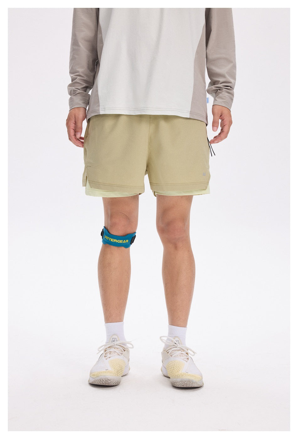 Front view of a model wearing khaki layered running shorts with a light-colored inner short.