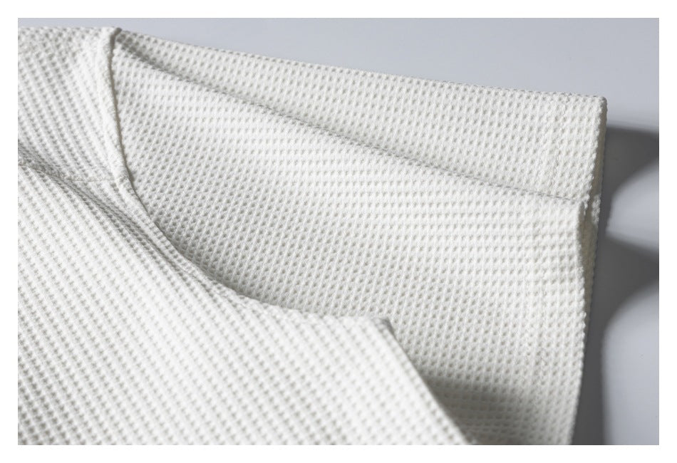 Close-up of ivory waffle-knit fabric folded to show a finished edge.