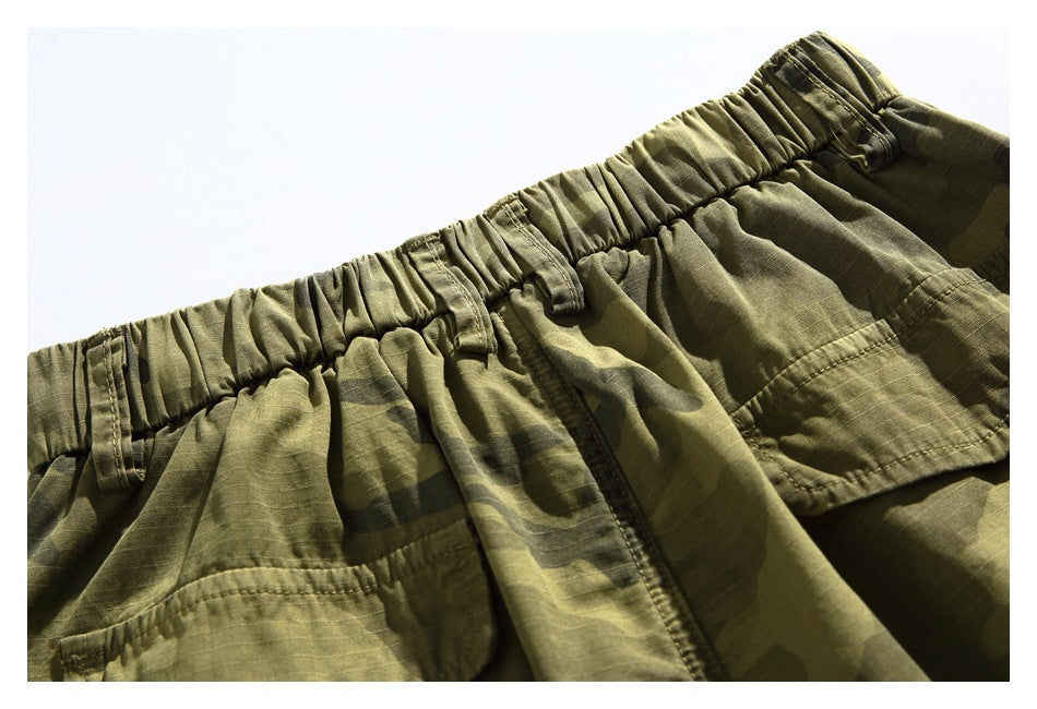 Close-up of the gathered elastic waistband and belt loops on olive camouflage shorts.