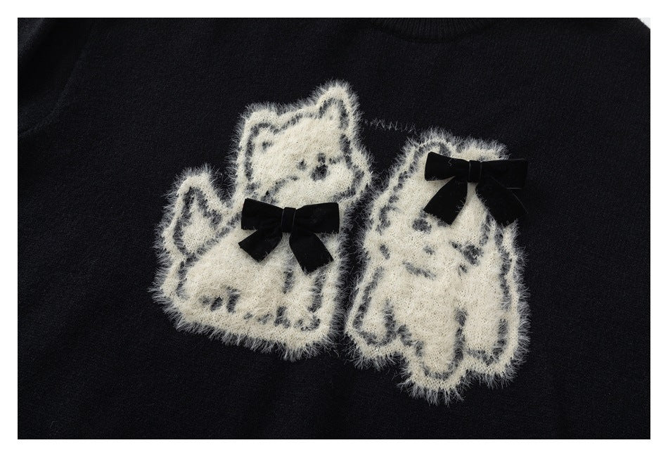 Black sweater front with two fuzzy white cat motifs, each decorated with a black bow.