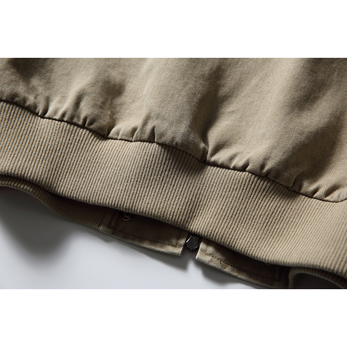 Close-up of the jacket's ribbed hem, gathered fabric, and zipper end.