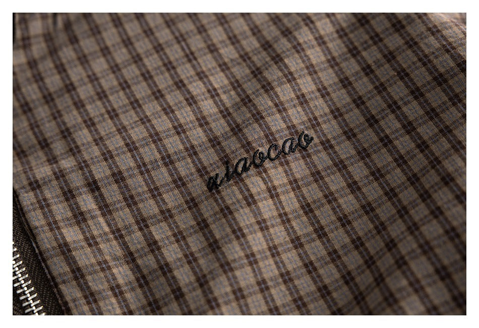Close-up of beige and brown plaid jacket fabric with small black embroidered script.