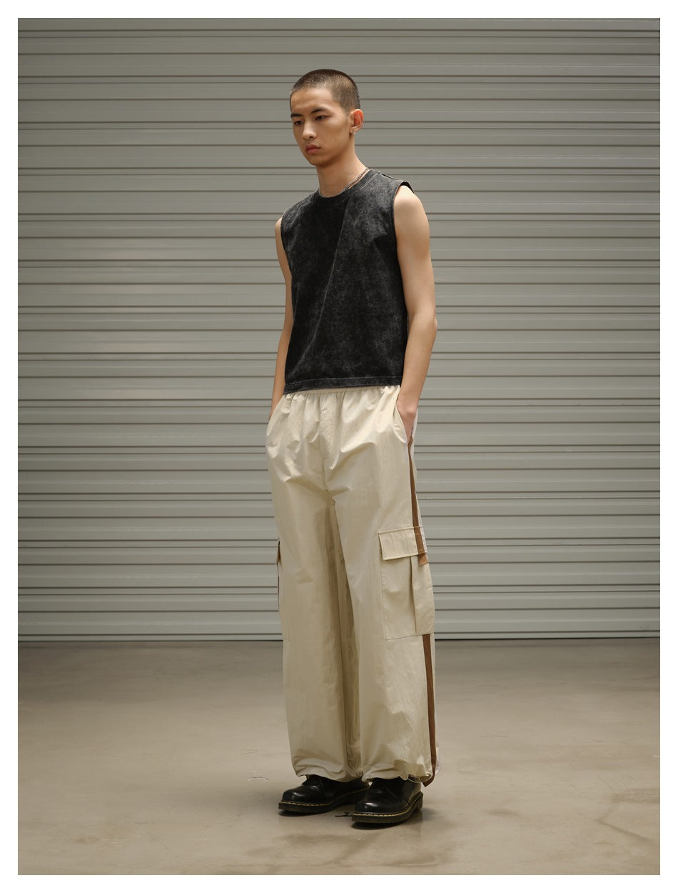 Three-quarter view of a model wearing a black sleeveless top and loose beige cargo pants with cargo pockets.