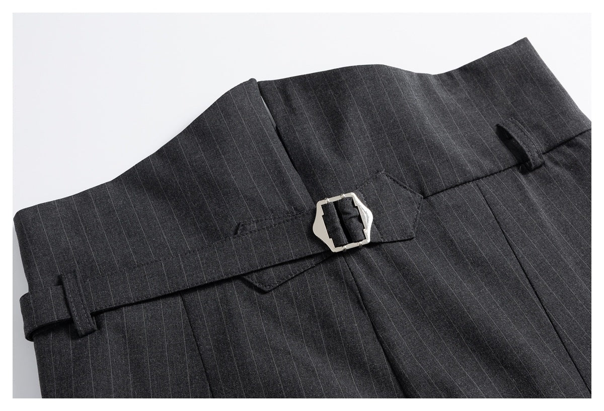 Waist detail of charcoal pinstripe trousers with belt loops and a matching strap fastened by a silver buckle.