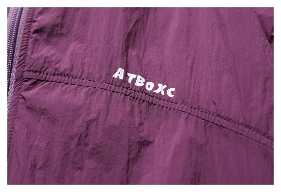 Close-up of white lettering on the chest of a plum jacket beside its front zipper.