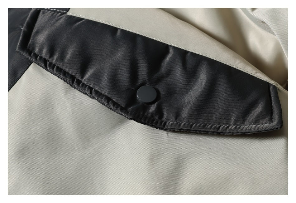 Close-up of a black flap pocket with a snap button on the beige jacket panel.