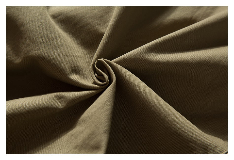 Close-up of khaki trouser fabric gathered into a twist to show its surface and drape.