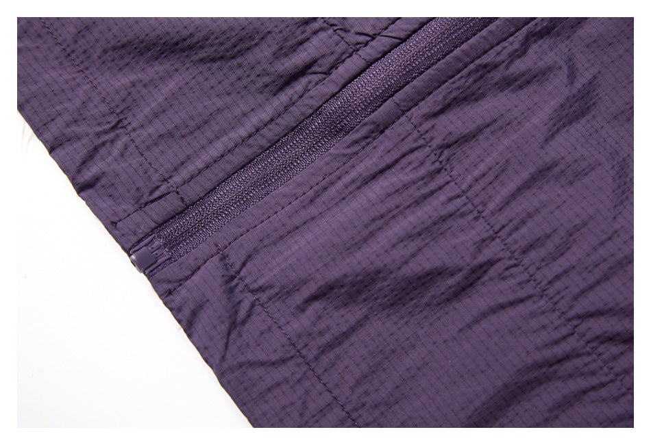 Close-up of a dark purple jacket showing a diagonal zipper and fine grid-textured fabric.