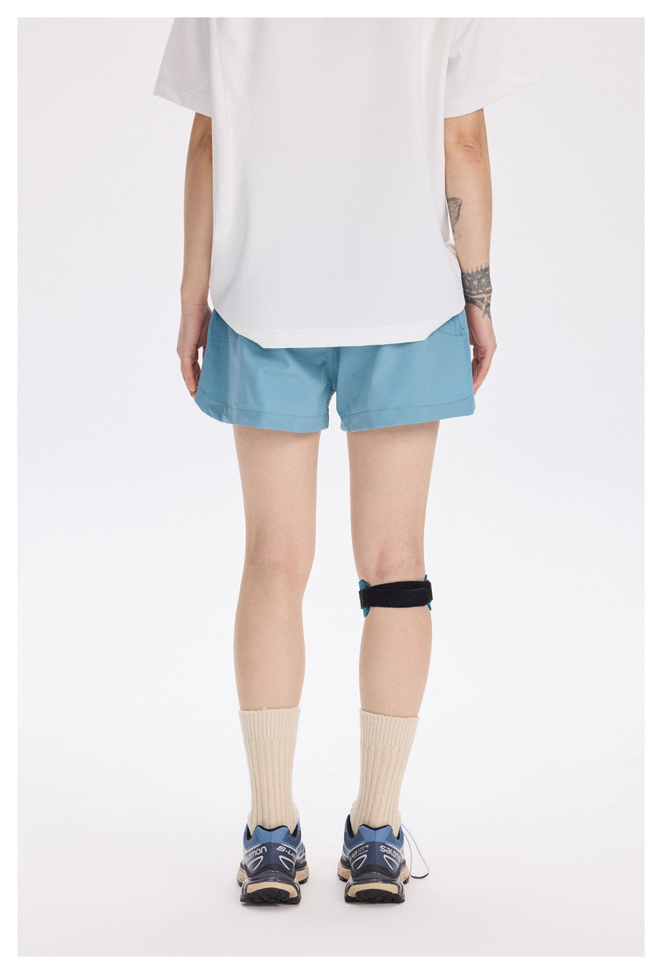 Rear view of a model wearing light teal running shorts with a clean, simple back and straight hems.