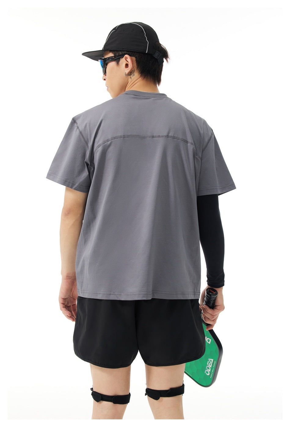 Back view of a model wearing a charcoal-gray short-sleeve shirt with a curved seam across the upper back.