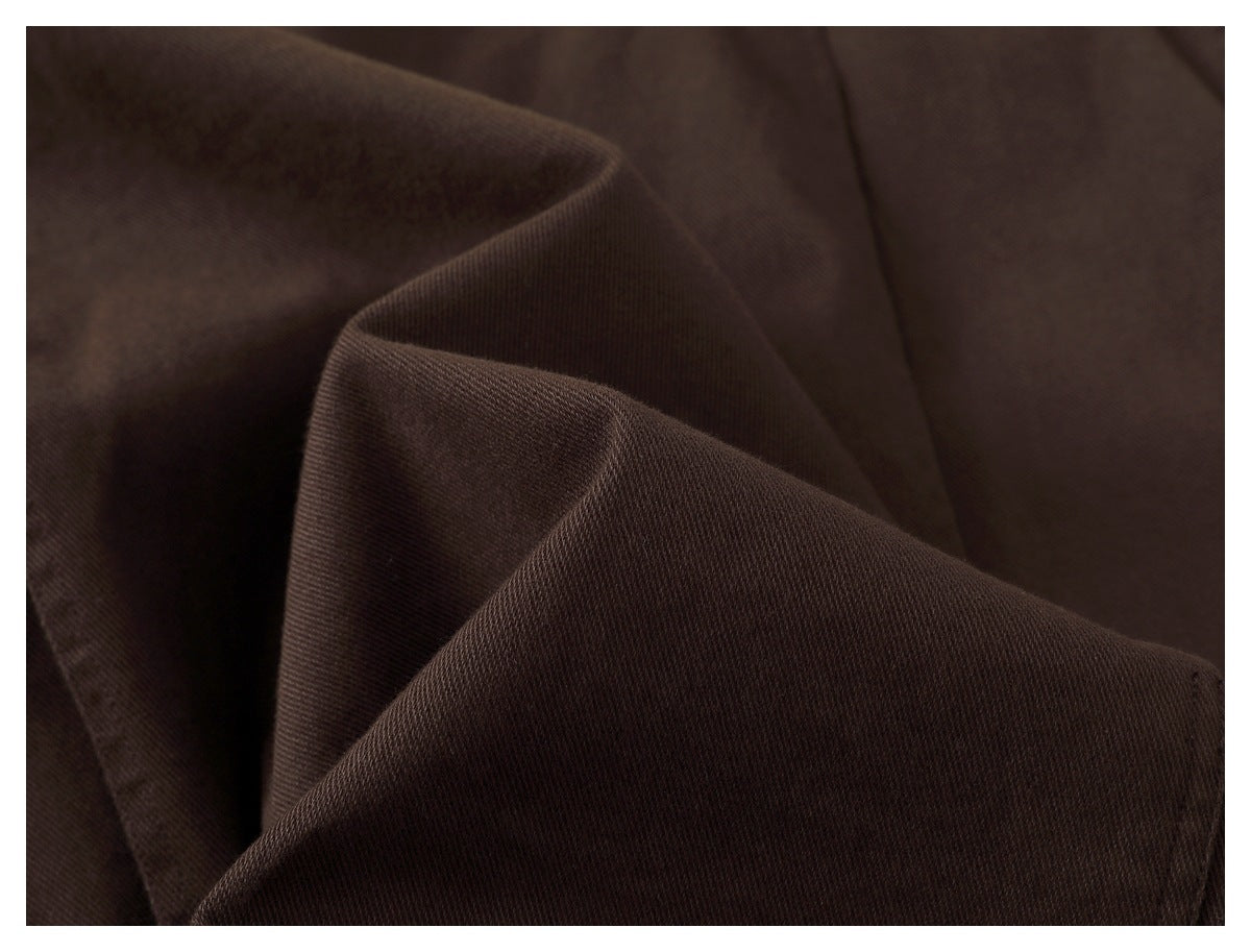 Close-up of dark brown fabric folded to show its fine diagonal weave.