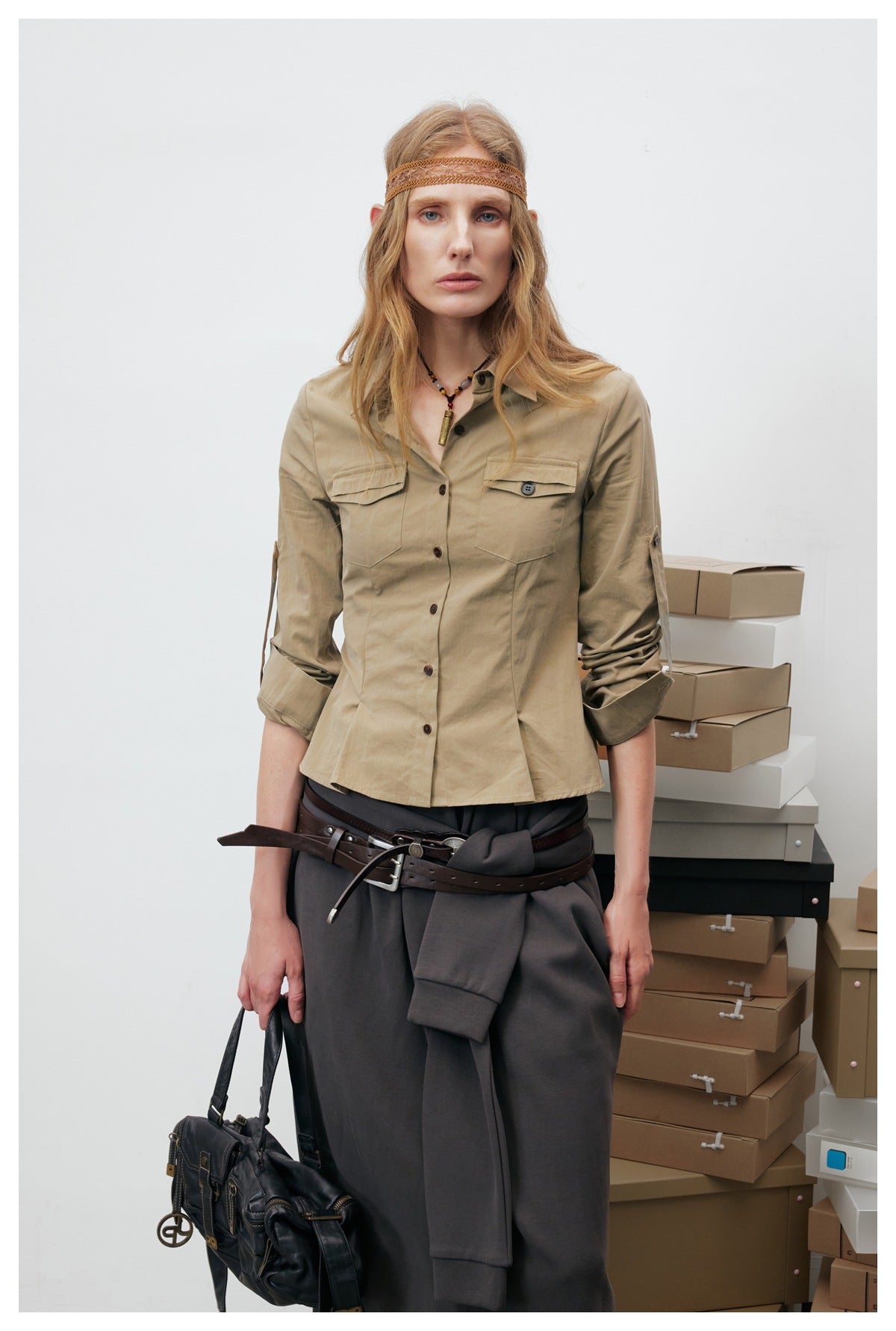 Model wearing a khaki button-front shirt with two flap chest pockets and rolled sleeves, shown from the front.