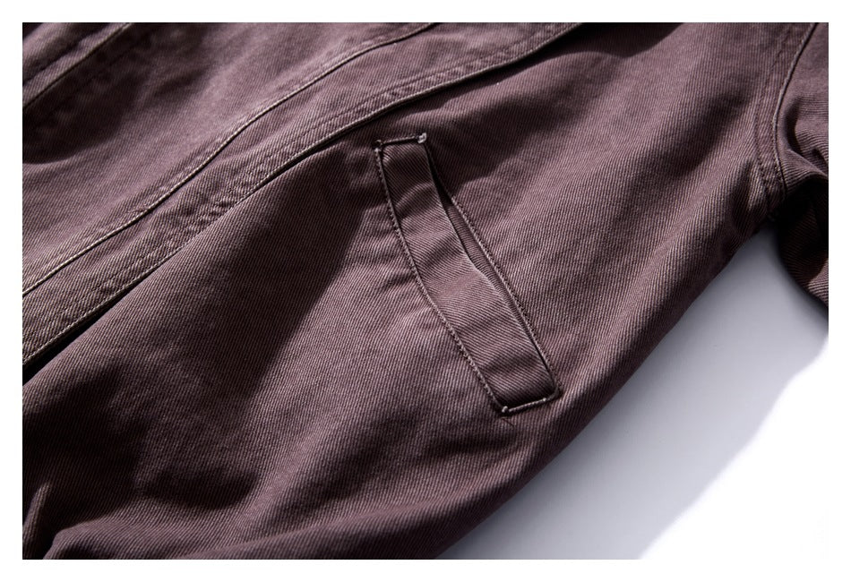 Close-up of a muted plum-brown jacket with a narrow slanted pocket and stitched seams.