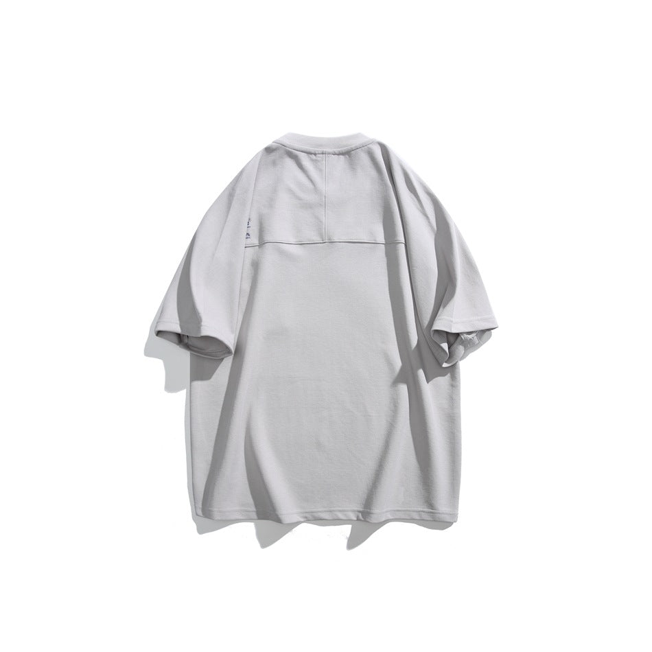 Back of light gray short-sleeve T-shirt with horizontal upper-back seam and small print near the sleeve