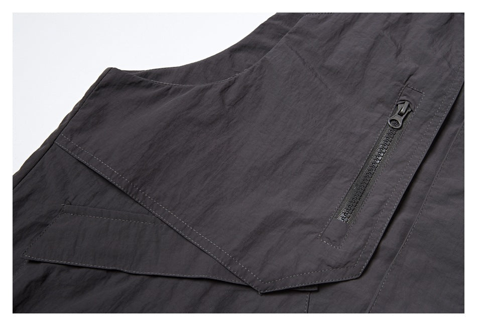 Close-up of a flap pocket and vertical zip pocket on the charcoal vest.