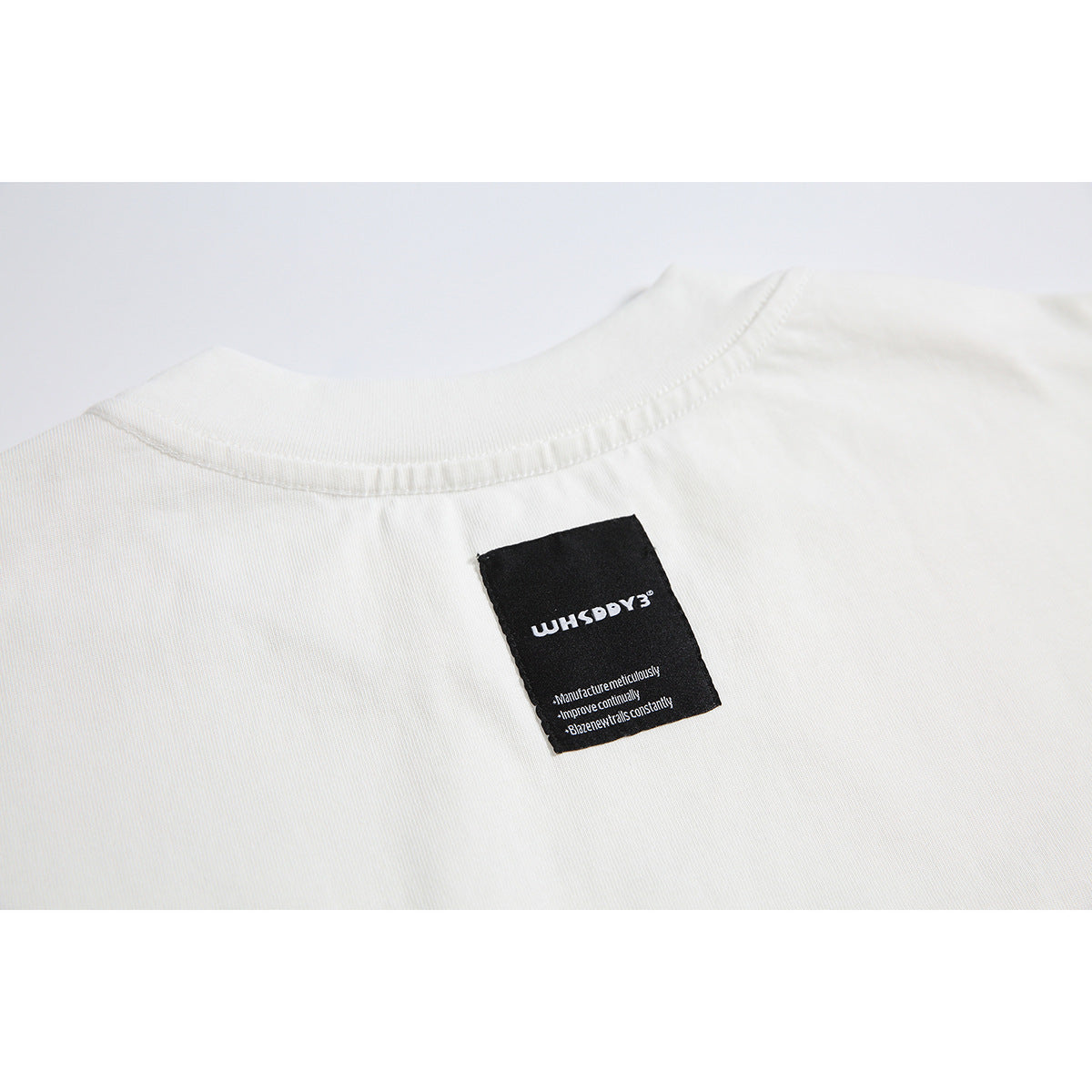 Close-up of the T-shirt's inside back neckline and black sewn-in label with small English text.
