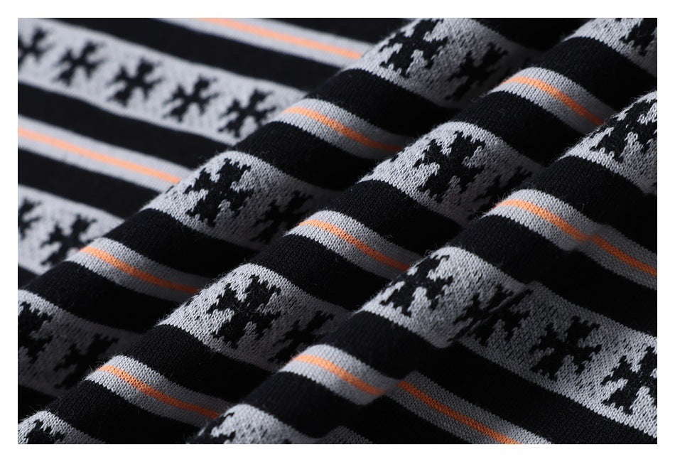 Close-up of black knit fabric with gray snowflake bands and thin orange stripes.