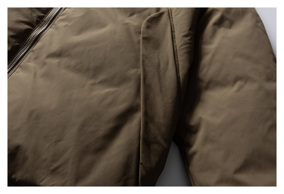 Close-up of a brown jacket's front seam, panel, and sleeve, with part of the zipper visible.