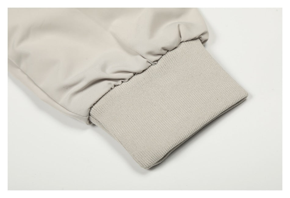 Close-up of a light beige sleeve gathered into a wide ribbed knit cuff.