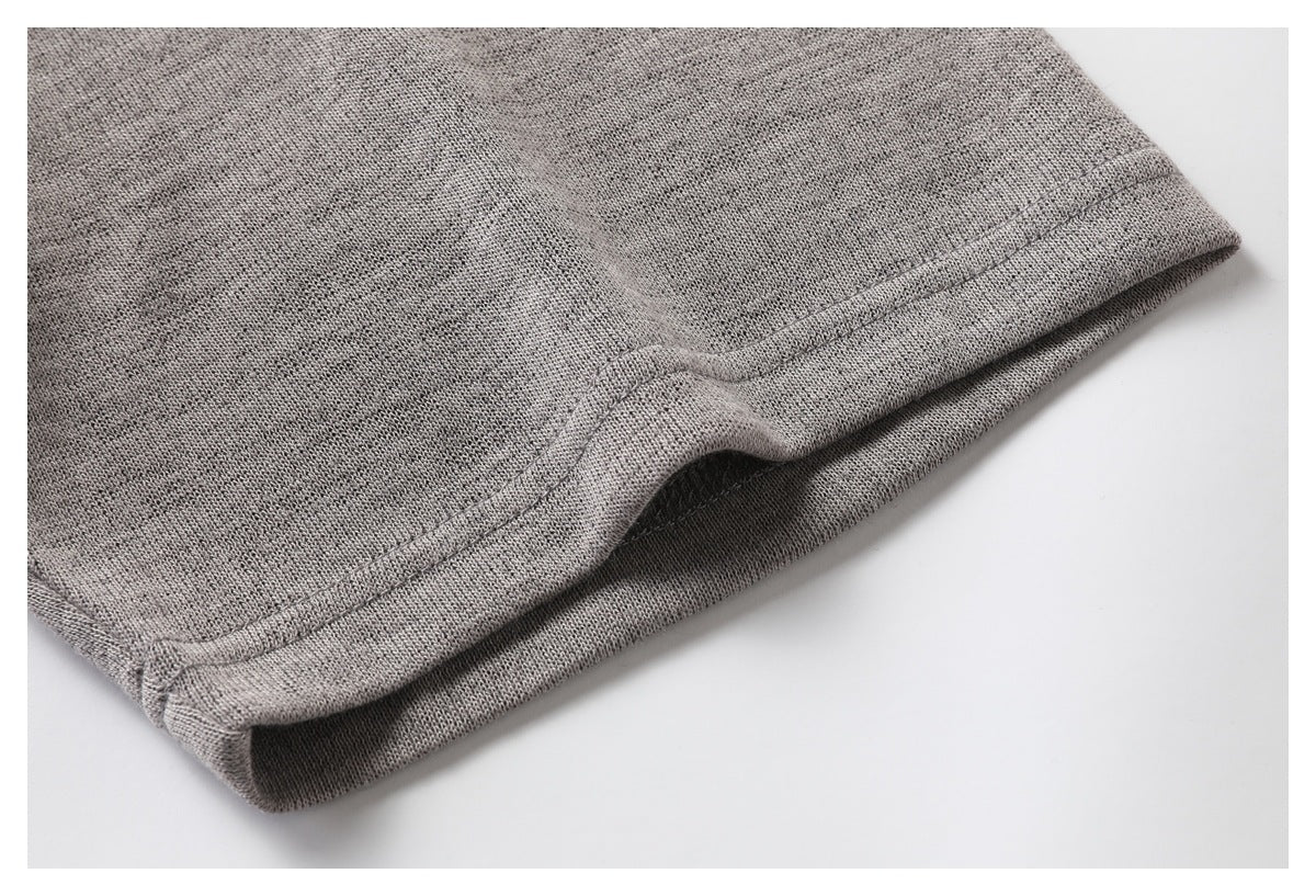 Close-up of a heather gray garment hem with double stitching and a folded edge.