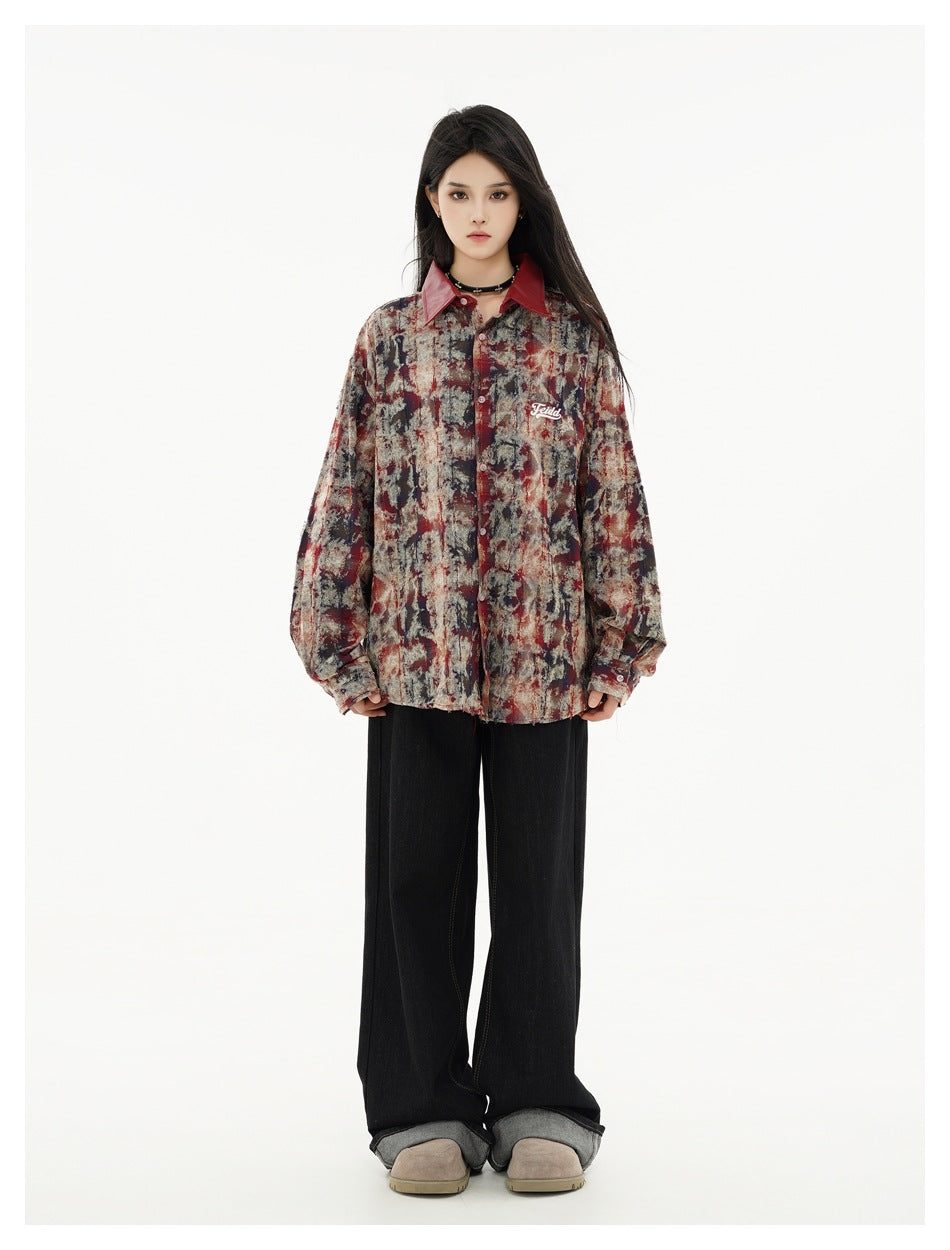 Front view of a model wearing an oversized red-collar abstract-print button-up shirt with black wide-leg jeans.