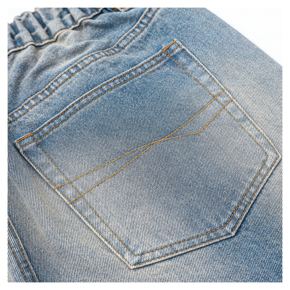 Close-up of a blue denim back pocket with orange contrast stitching.