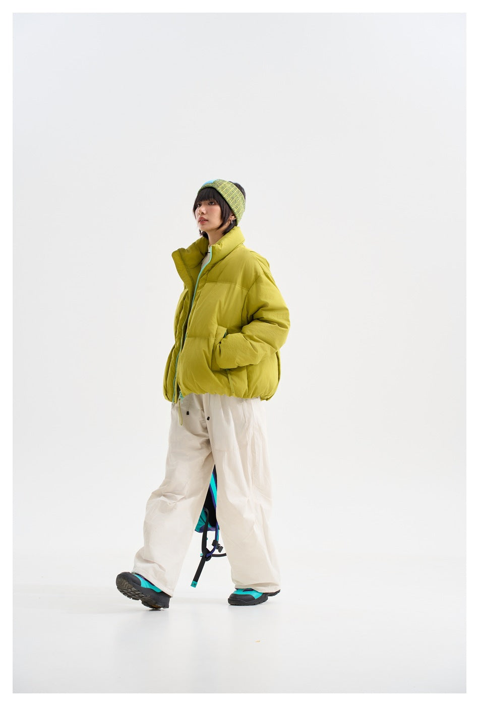 Model in a lime-yellow puffer jacket, shown from a three-quarter angle with white trousers.