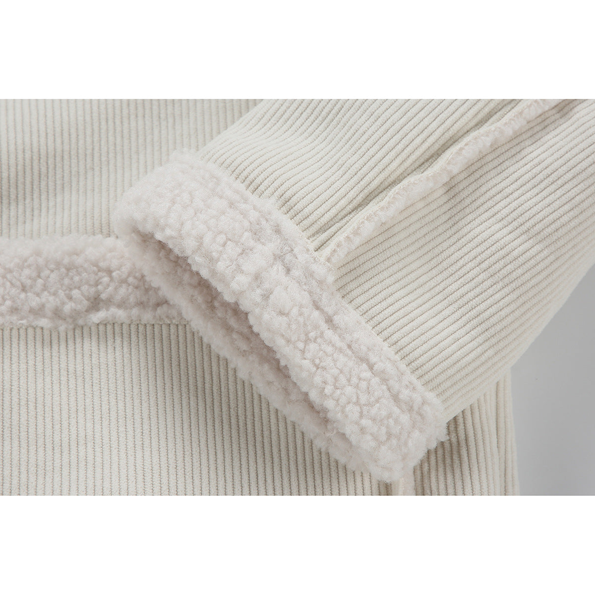 Close-up of an ivory jacket cuff showing plush lining against ribbed corduroy fabric.