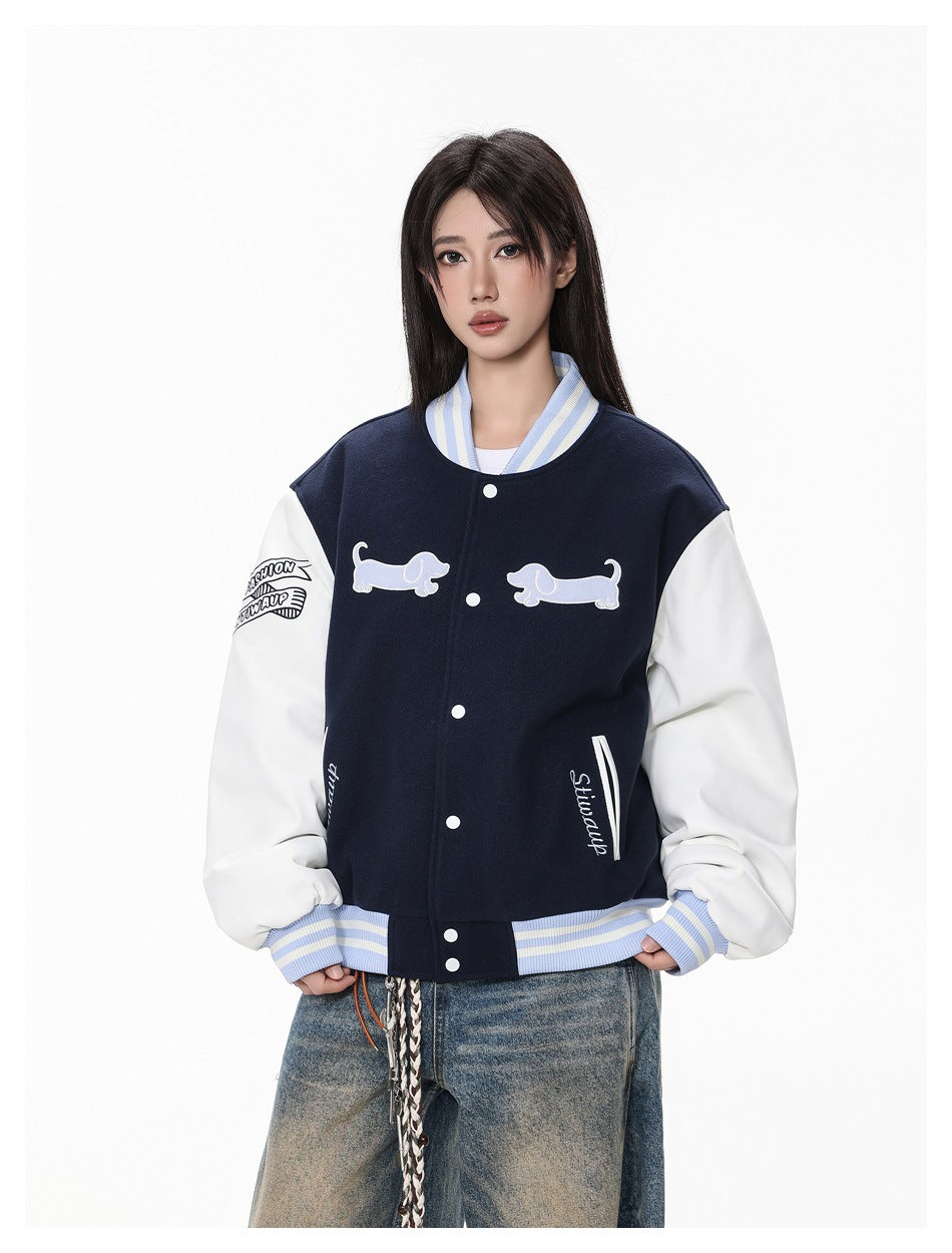 Front view of a model wearing a navy and white varsity jacket with dog appliqués and striped ribbed trim.