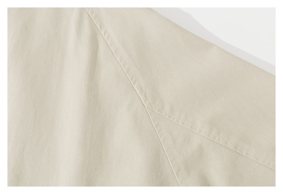 Close-up of the beige jacket's sleeve and curved raglan seam stitching.