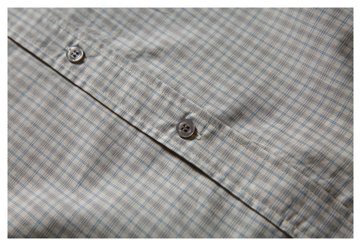 Close-up of the button placket on a beige shirt with a fine blue-gray plaid pattern.
