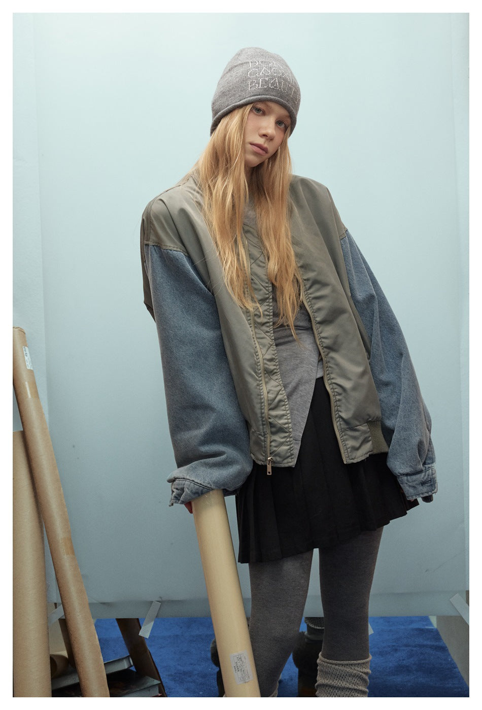 Closer view of a model wearing an oversized gray-green bomber jacket with blue denim sleeves.