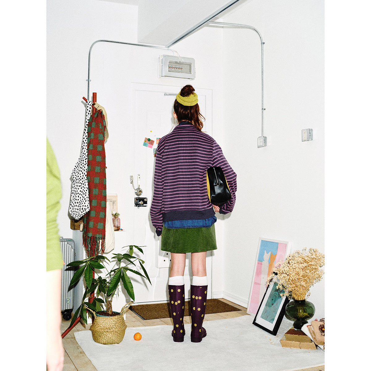 Back view of a model wearing a purple and black striped jacket with a dark hem and cuffs.