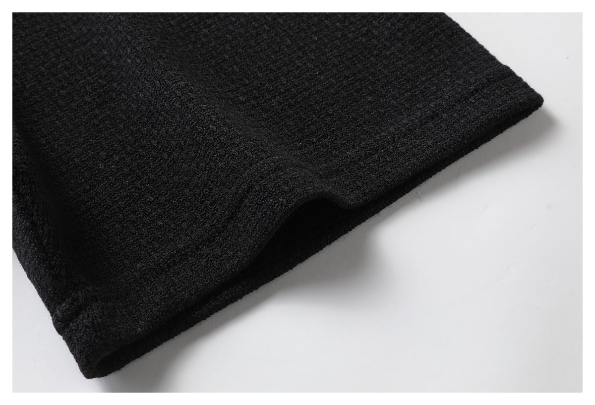 Close-up of the black shirt's finished sleeve hem and textured fabric.