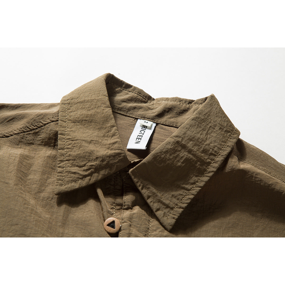 Close-up of an olive-brown shirt collar, button, stitching, and sewn-in neck label.